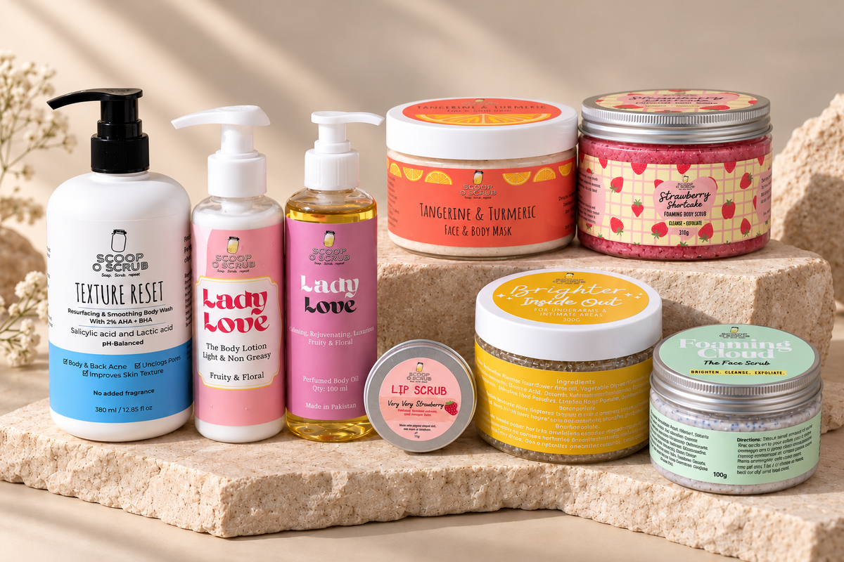 A collection of Bath Body Works bath and body products arranged on stacked stone blocks, including a Texture Reset body wash, Lady Love body lotion and body cream, a Tangerine & Turmeric body & foot milk, a Strawberry & Raspberry bath salt, a Brighten Sunshine body scrub, and a Face Pure Polish jar.