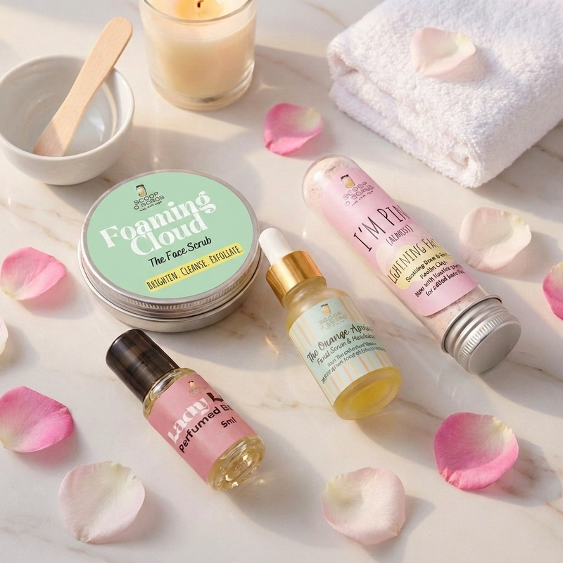 face scrub tin, perfume bottles, and a candle on a marble surface with rose petals.